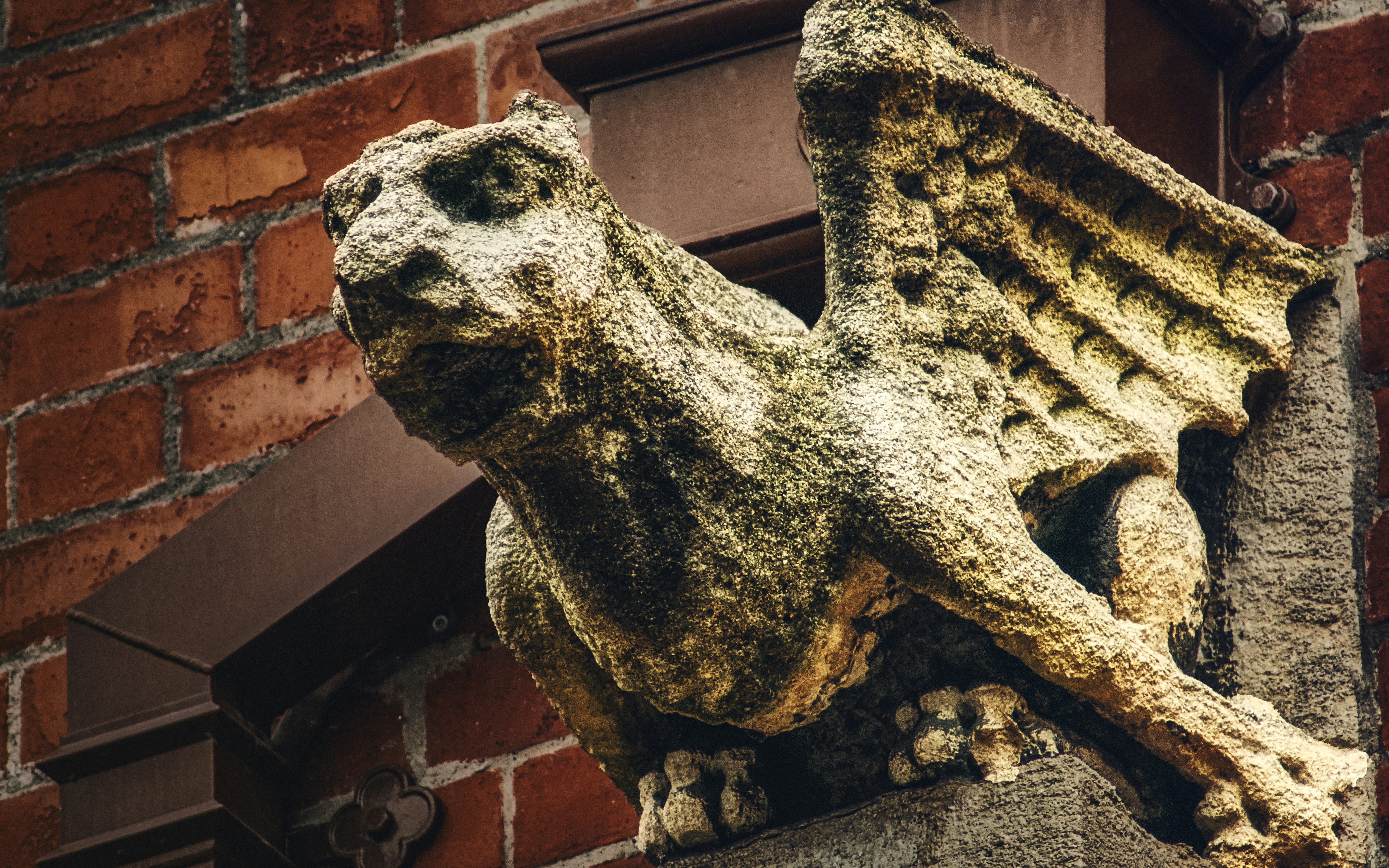 gray concrete statue near brown brick wall